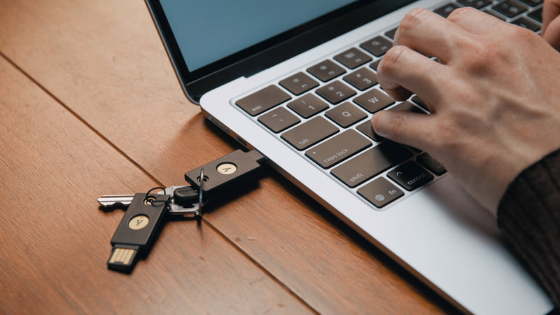 木製テーブルの上のノートパソコンとYubiKey
