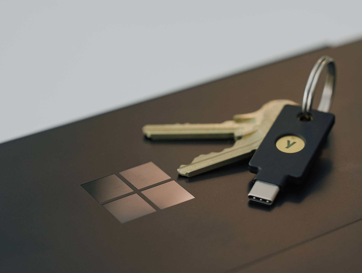 Windowsロゴのあるノートパソコンの上に置かれた、鍵束付きのUSB-C YubiKey