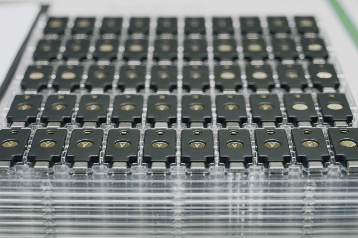 トレイに並ぶ大量の YubiKey セキュリティキー（製造・出荷時）