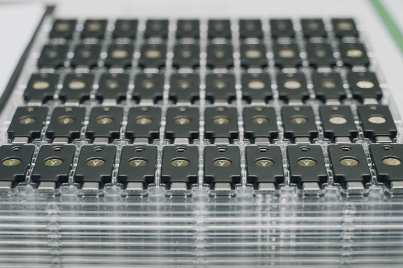 トレイに並ぶ大量の YubiKey セキュリティキー（製造・出荷時）